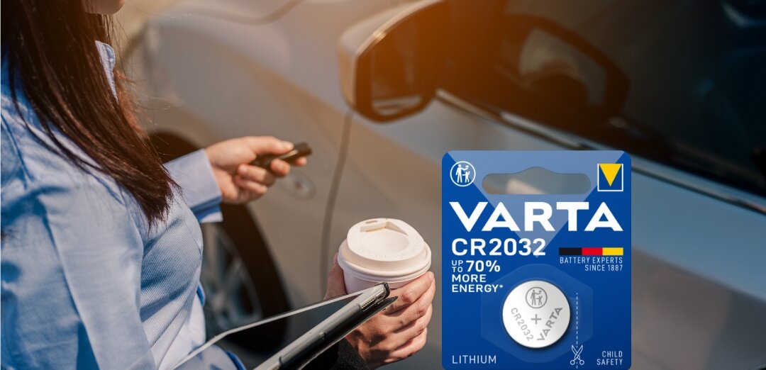 Kobieta przy samochodzie z kluczykami, kawą i tabletem, obok opakowanie baterii VARTA CR2032.