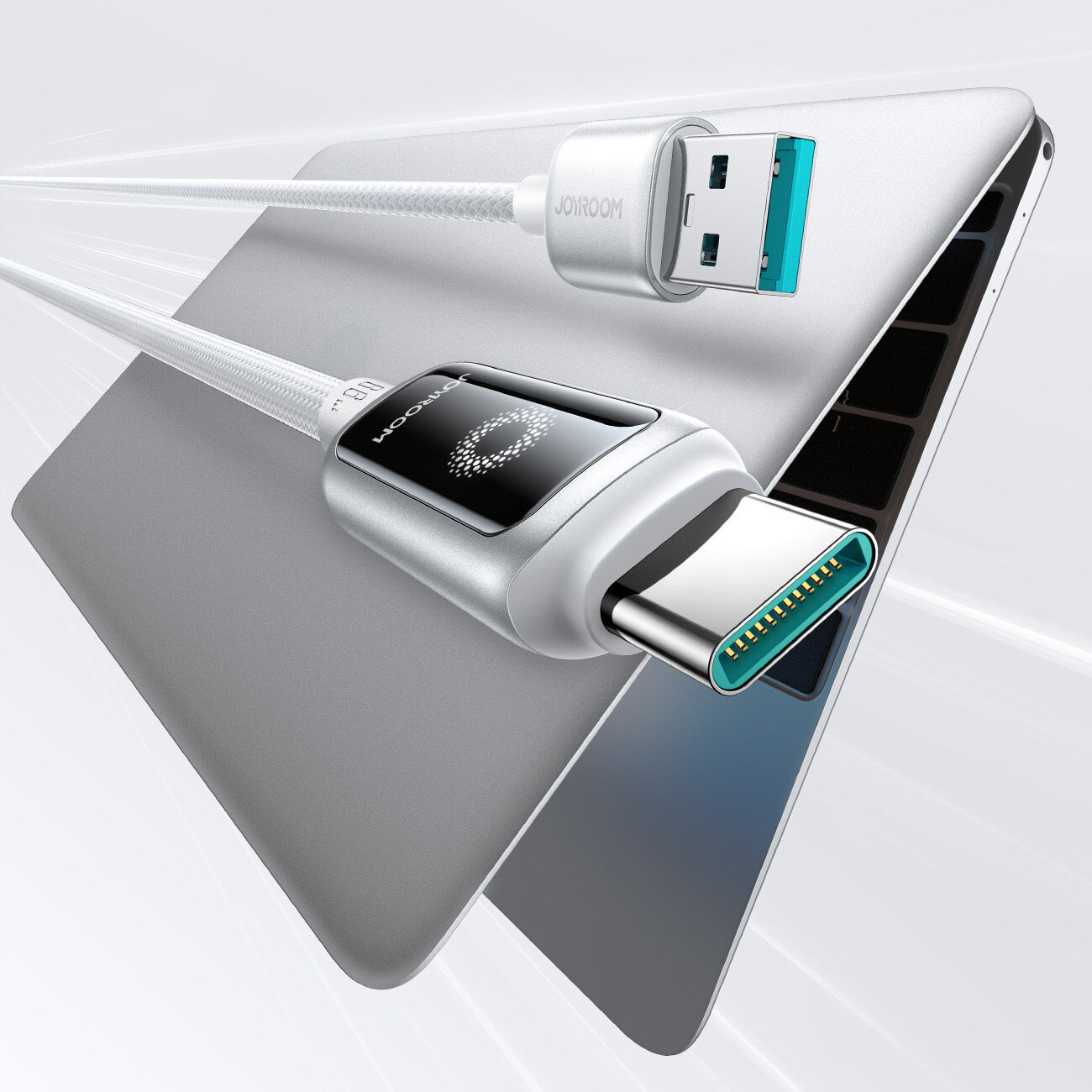 Obraz przedstawia dwa złącza kabla USB, jedno USB-A i drugie USB-C, z widocznym napisem \'JOOM\'. Kabel jest podłączony do laptopa, a jego powierzchnia jest opleciona.
