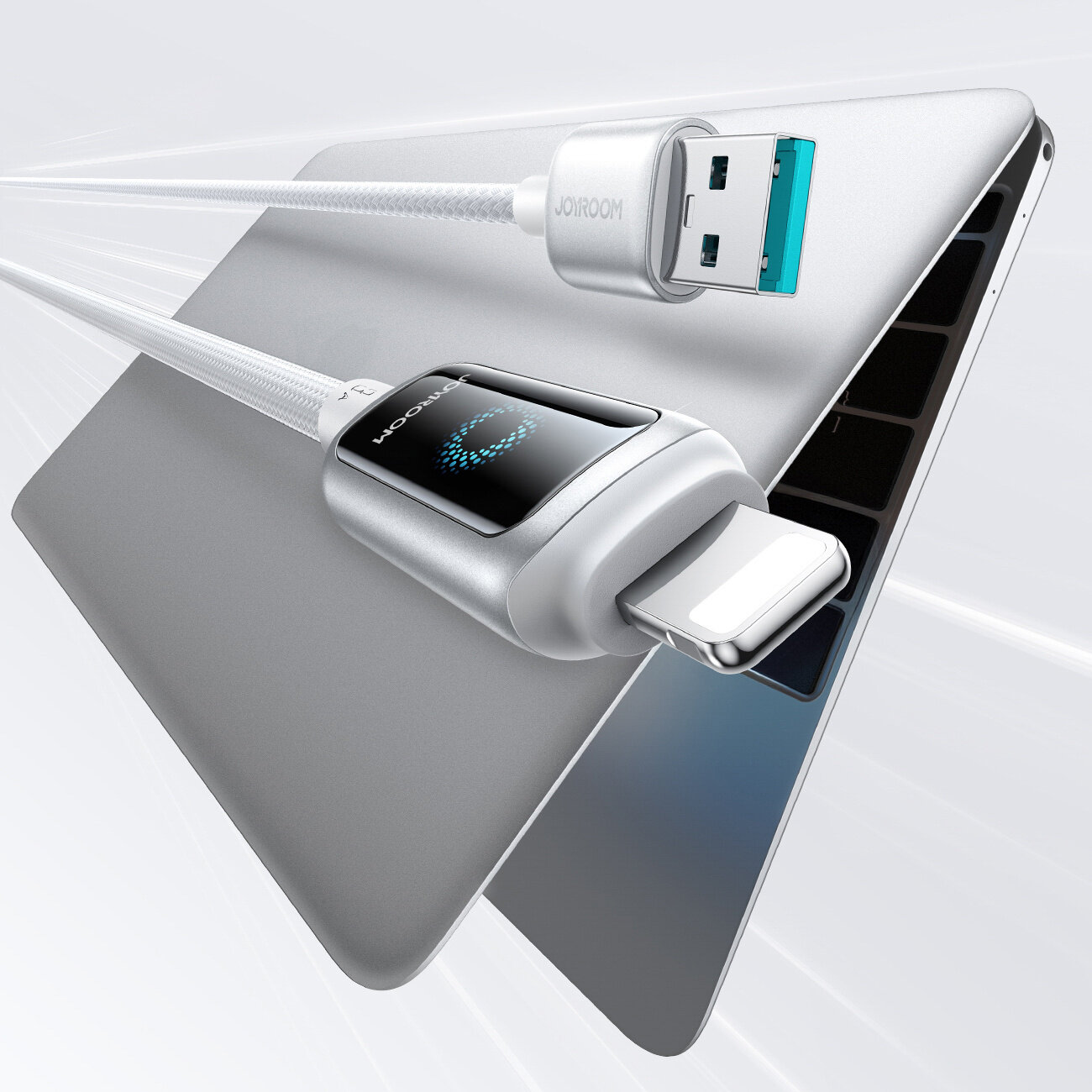 Na obrazie widoczny jest kabel USB-A - Lightning z metalowymi końcówkami, podłączony do laptopa. Na jednej z końcówek znajduje się logo \'JOYROOM\'.
