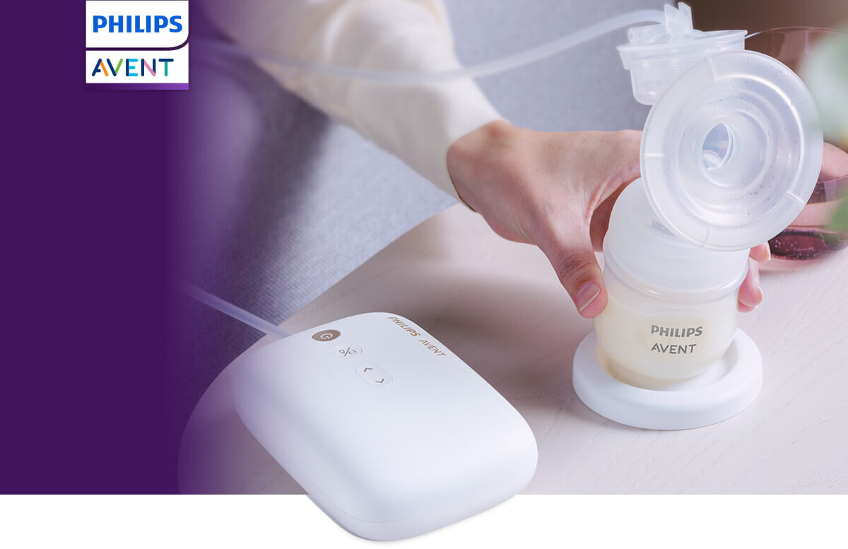 Na obrazie widoczny jest laktator z logo Philips Avent, trzymany przez osobę. Obok znajduje się biały, bezprzewodowy moduł sterujący z przyciskami.