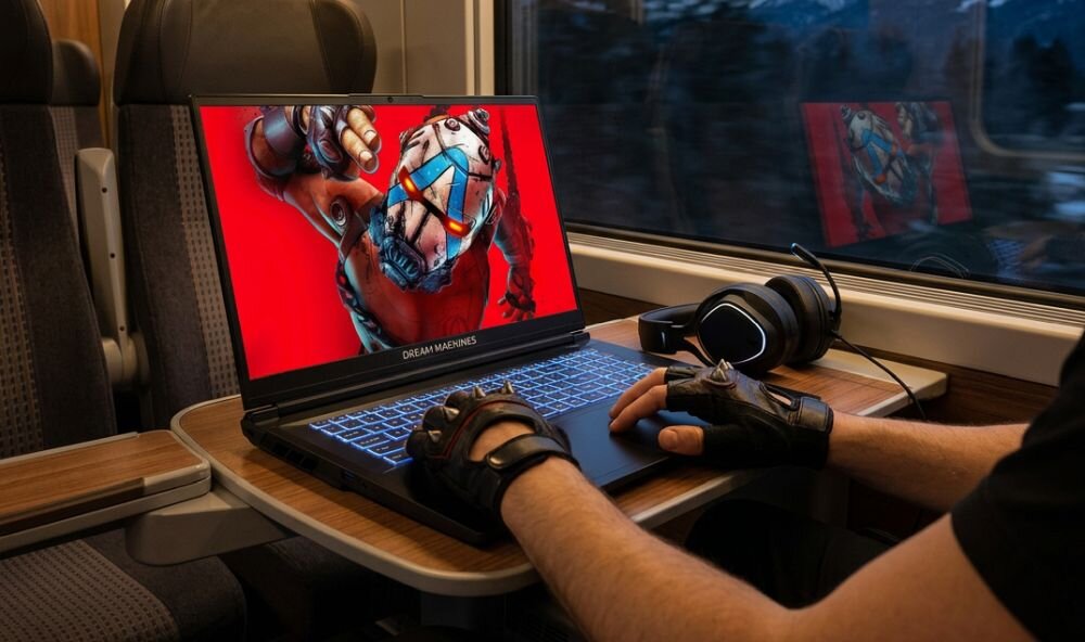 Osoba gra na laptopie DREAMMACHINES RT5050 z podświetlaną klawiaturą podczas podróży pociągiem - jasność 300 nitów
