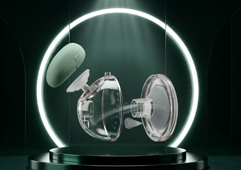 Obraz przedstawia rozłożony laktator z przezroczystymi elementami i zieloną częścią, umieszczony na ciemnym tle z jasnym okręgiem w tle.