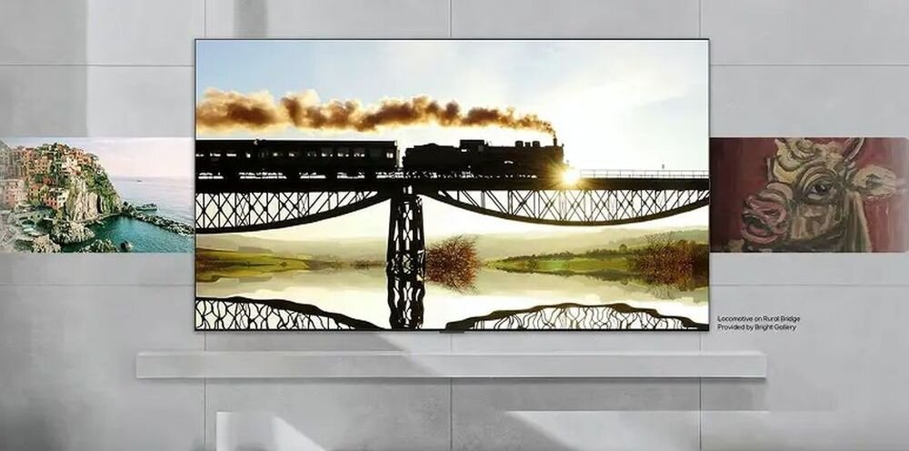 Telewizor wyświetla obraz pociągu na moście z odbiciem w wodzie poniżej. Na ekranie widoczny jest napis: \'Locomotive on Buran Bridge Provided by Bright Gallery\'.