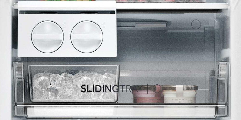Wnętrze zamrażarki z widocznym pojemnikiem na lód oraz napisem \'SLIDING TRAY\'.
