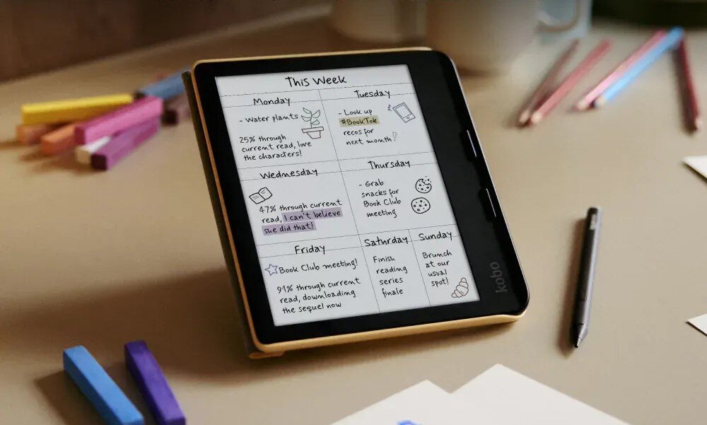 Na zdjęciu widać czytnik e-booków z wyświetlaczem, na którym znajduje się tygodniowy plan z zadaniami na każdy dzień. Obok leżą kolorowe kredki i długopis.