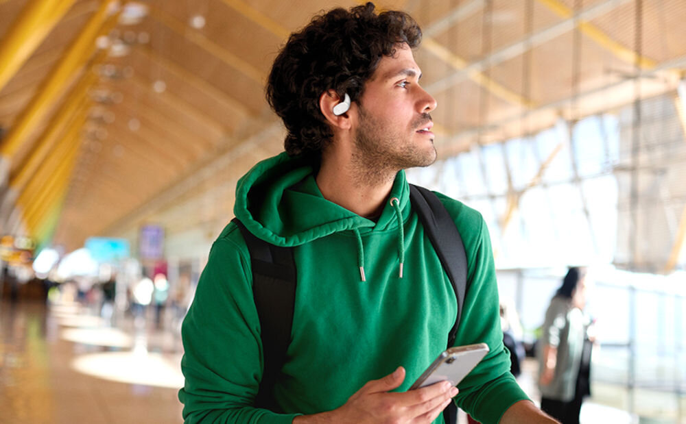 JBL Sense Lite lekka konstrukcja silikonowa komfort i izolacja dźwięku, osoba z założonymi słuchawkami trzymająca telefon w dłoni