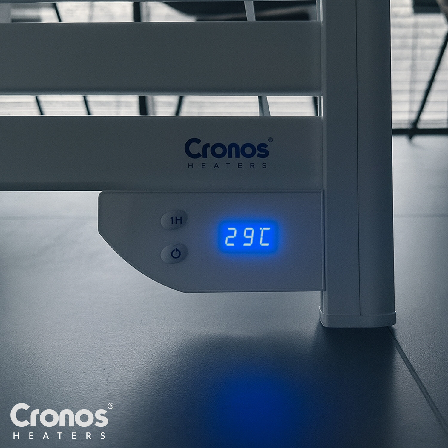 Na obrazie widoczny jest fragment grzejnika z logo \'Cronos HEATERS\'. Wyświetlacz pokazuje temperaturę 29°C, a obok znajdują się przyciski z oznaczeniami \'1H\' i symbolem włącznika.