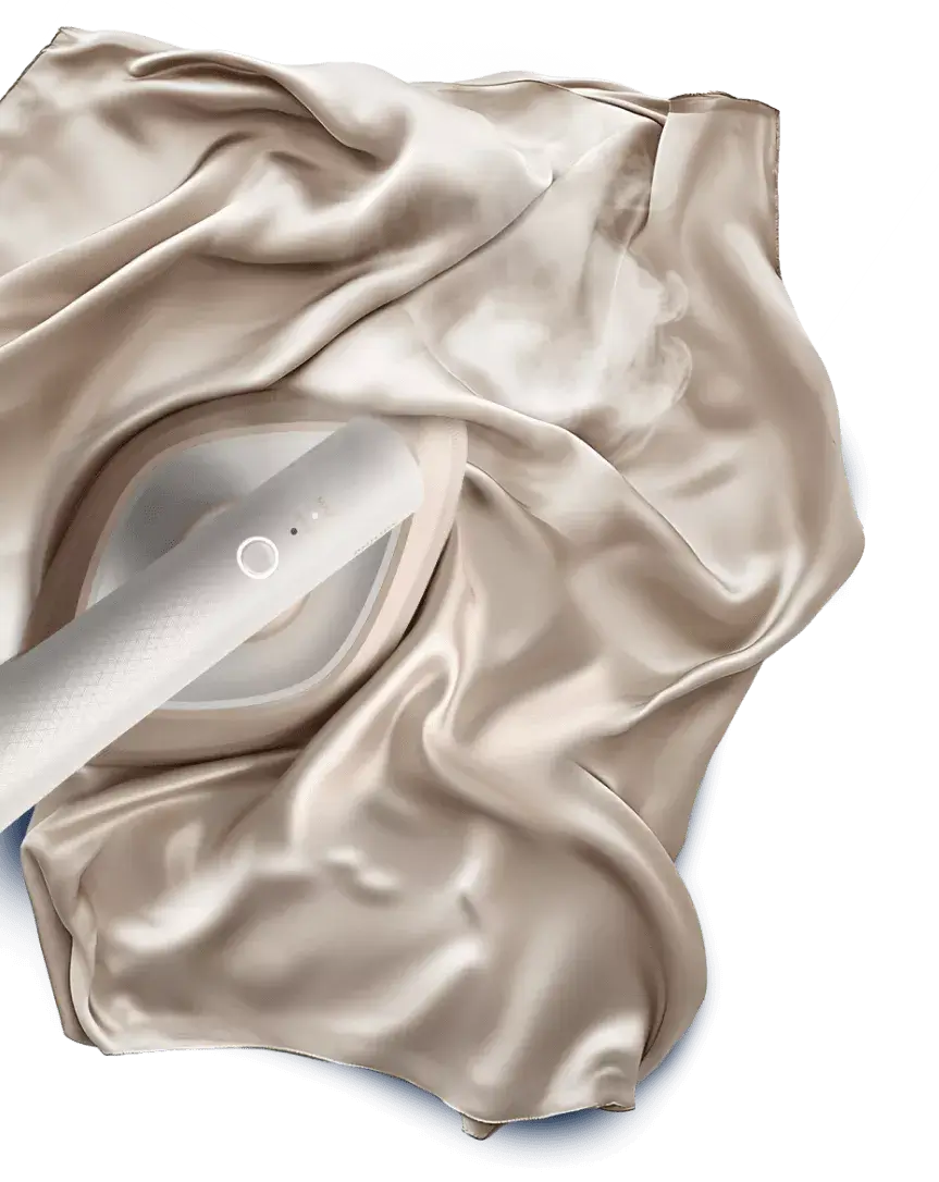 Na obrazie widać parownicę do ubrań, która jest używana na gładkiej, jasnej tkaninie. Parownica emituje parę, co sugeruje jej działanie.