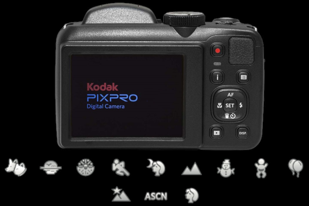 Tył czarnego aparatu cyfrowego z wyświetlaczem pokazującym logo \'Kodak PIXPRO Digital Camera\'. Poniżej ekranu znajdują się różne ikony trybów fotograficznych, w tym ASCN.