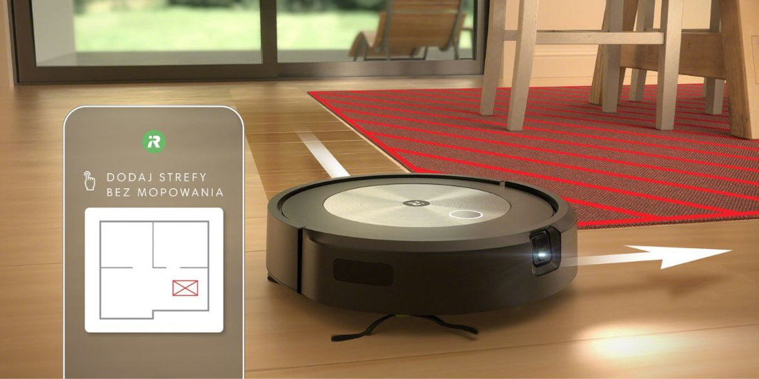 Robot sprzątający na drewnianej podłodze obok czerwonego dywanu, z widocznym interfejsem pokazującym opcję \'DODAJ STREFY BEZ MOPOWANIA\'.