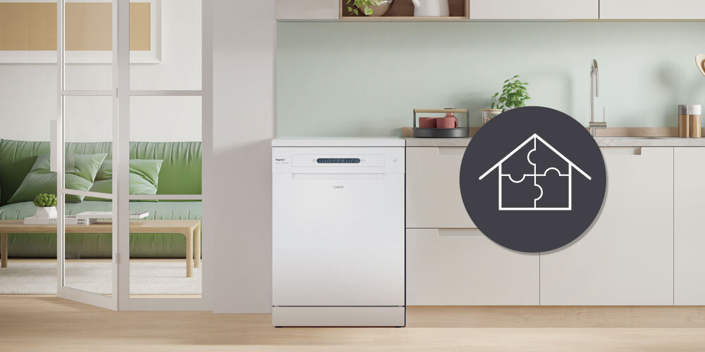 Na obrazie znajduje się biała zmywarka w nowoczesnej kuchni, obok której widoczny jest okrągły symbol domu z elementami układanki. W tle widać część salonu z zieloną sofą.