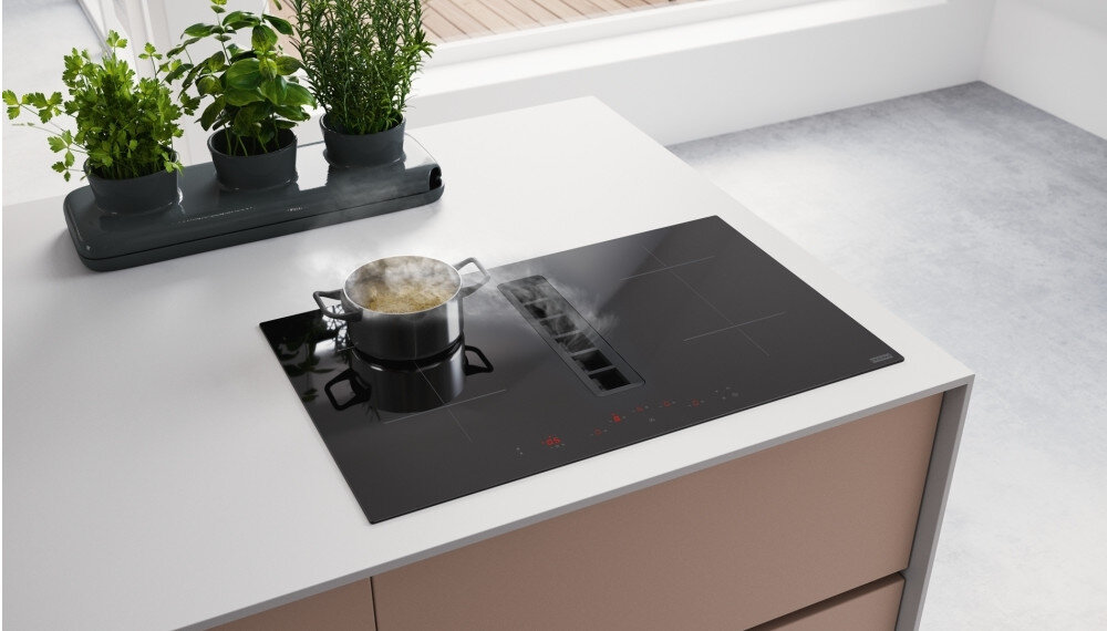 PŁYTA FRANKE Ellipse FMA 8372 4RC R HI 340.0731.879 Płyta indukcyjna z wbudowanym wyciągiem, na której smażone są warzywa na patelni, a para jest zasysana przez centralny otwór. Urządzenie jest zamontowane w jasnym blacie kuchennym