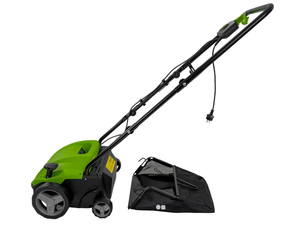 Na obrazie widoczny jest zielony wertykulator elektryczny z czarnym uchwytem i przewodem zasilającym. Obok urządzenia znajduje się czarny kosz na trawę.