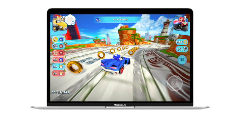 Laptop z wyświetlaczem pokazującym grę wyścigową z postacią w niebieskim samochodzie na torze. Na ekranie widoczne są złote pierścienie oraz elementy interfejsu gry, takie jak licznik czasu i pozycje graczy.