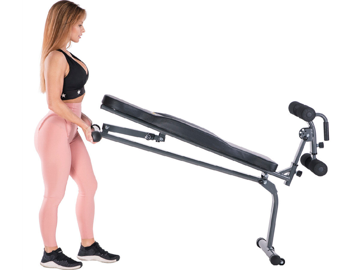 Kobieta w sportowym stroju trzyma ławkę do ćwiczeń z regulowanym oparciem i wałkami na nogi. Ławka jest w kolorze czarnym z metalową ramą.