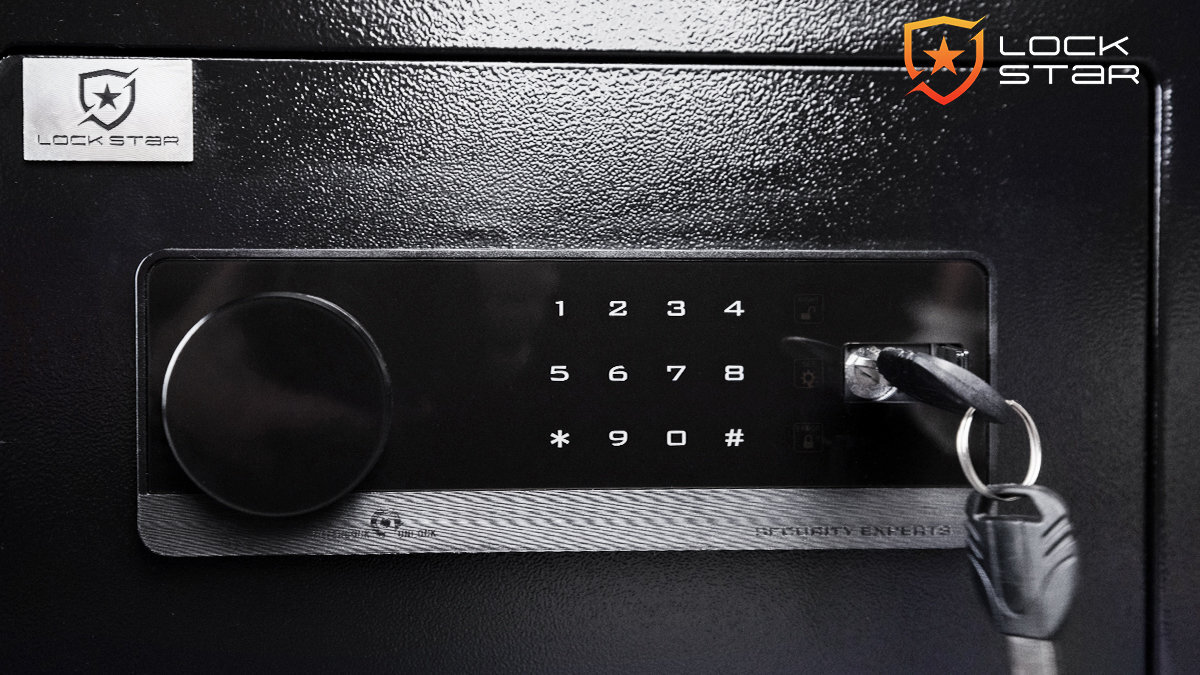 Czarny sejf z elektronicznym panelem numerycznym, na którym widoczne są cyfry od 1 do 9 oraz symbole * i #. Obok panelu znajduje się klucz w zamku, a w rogu widoczne jest logo \'LOCK STAR\'.