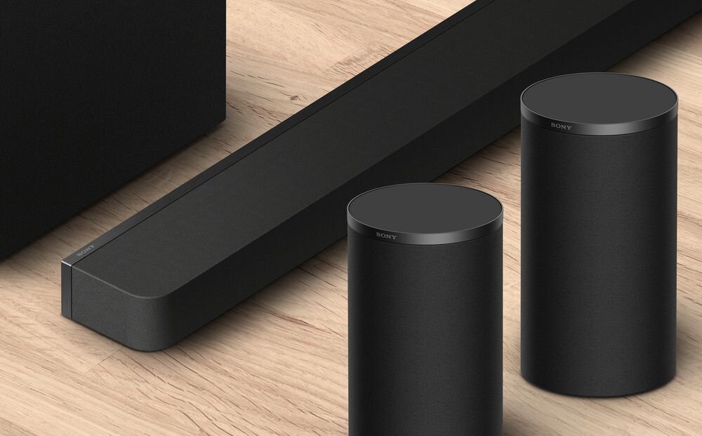 SONY SA-RS9 bezprzewodowe kolumny głośnikowe dźwięk przestrzenny 360 Spatial Sound Mapping kino domowe, głośniki stojące na drewnianym podłożu obok soundbara