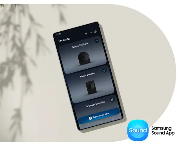 2026-hw-ls50h-samsung-sound-app 664x498 Na obrazie widoczny jest smartfon z aplikacją \'Samsung Sound App\' pokazującą listę urządzeń audio: \'Music Studio 5\', \'Music Studio 7\' i \'Q-Series Soundbar\'. W prawym dolnym rogu znajduje się logo \'Sound Samsung Sound App\'.
