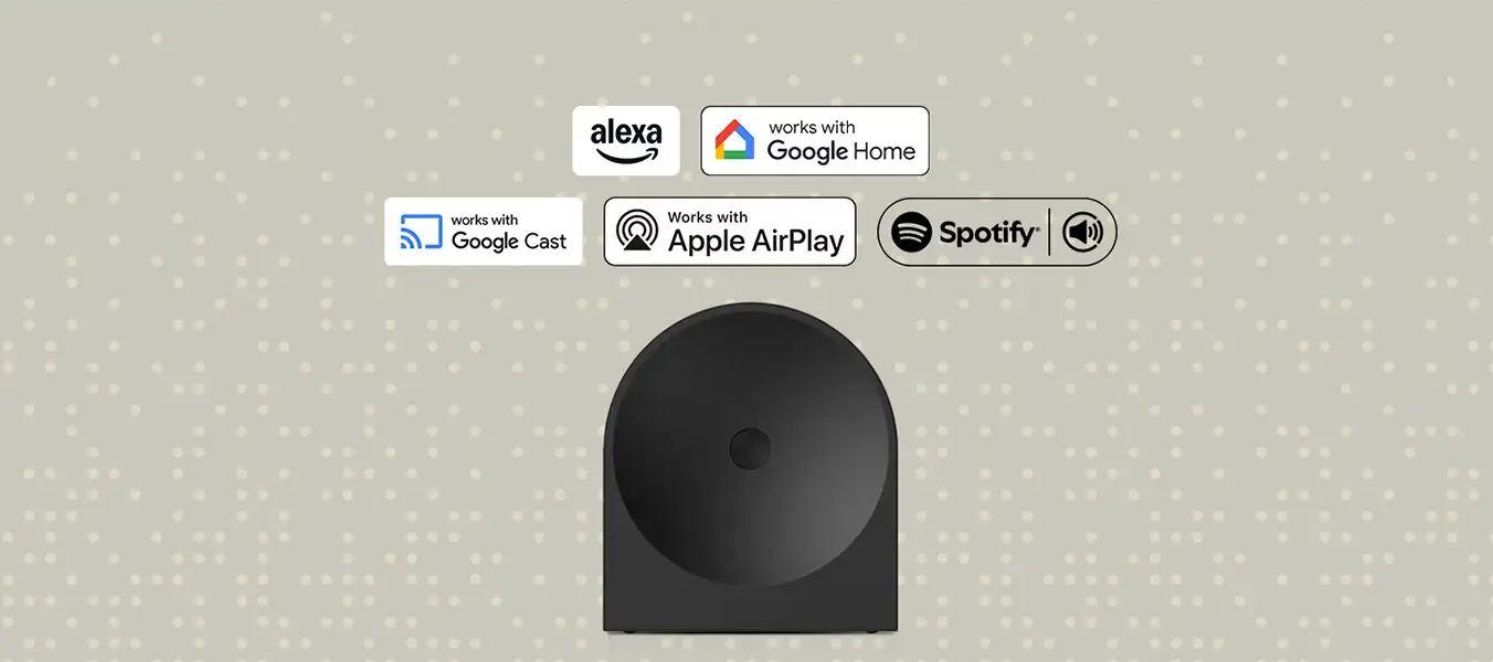 2026-hw-ls50h-voice-assistant-music-streaming-a-pc 1352x600 Na obrazie widoczny jest czarny głośnik na tle z jasnymi kropkami. Nad głośnikiem znajdują się logotypy: Alexa, works with Google Home, works with Google Cast, Works with Apple AirPlay, Spotify.