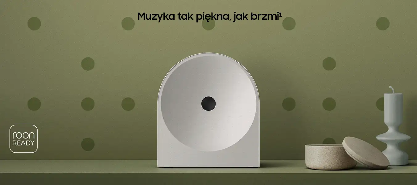 2026-hw-ls51h-kv-pc 1352x600 Na zielonym tle z kropkami znajduje się biały głośnik o okrągłym kształcie z czarnym środkiem. Obok głośnika widoczne są dwa dekoracyjne przedmioty oraz tekst \'Muzyka tak piękna, jak brzmi¹\'.