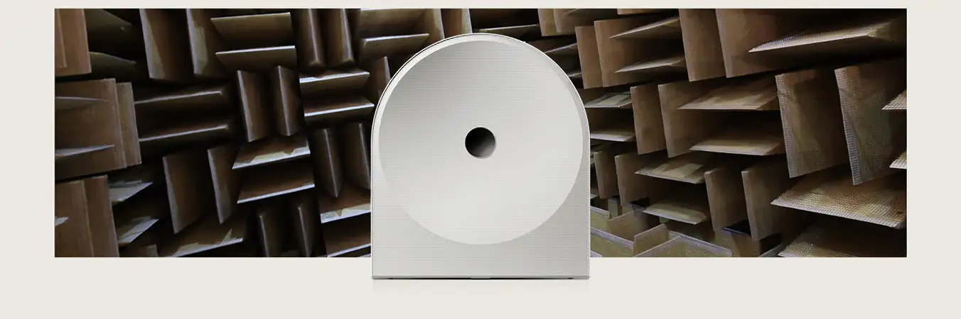 2026-hw-ls51h-samsung-audio-lab-pc 1352x450 Biały głośnik o nowoczesnym designie z okrągłym otworem na środku, umieszczony na tle pomieszczenia z panelami akustycznymi.