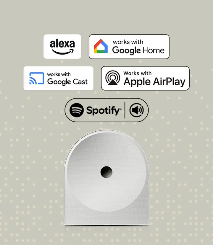 2026-hw-ls51h-voice-assistant-music-streaming-a-mo 720x830 Na obrazie widoczne są logotypy: \'alexa\', \'works with Google Home\', \'works with Google Cast\', \'Works with Apple AirPlay\', \'Spotify\'. Poniżej znajduje się biały głośnik o zaokrąglonym kształcie z centralnym otworem.