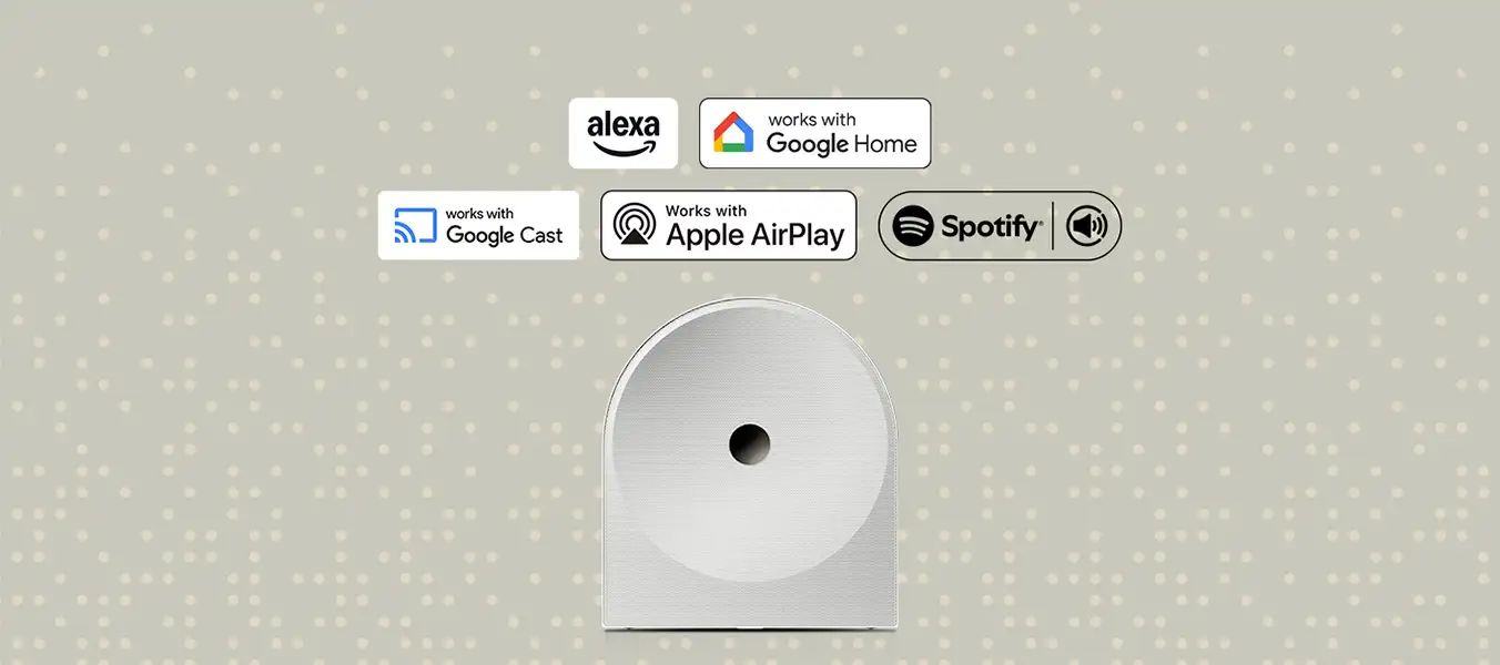 2026-hw-ls51h-voice-assistant-music-streaming-a-pc 1352x600 Na obrazie widoczny jest biały głośnik o zaokrąglonym kształcie z otworem na środku. Nad nim znajdują się logotypy: Alexa, works with Google Home, works with Google Cast, Works with Apple AirPlay, Spotify.