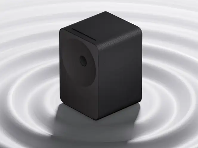 2026-hw-ls70h-ai-dynamic-bass-control-mo 664x498 Czarny głośnik o prostokątnym kształcie stoi na powierzchni z koncentrycznymi falami dźwiękowymi wokół niego.