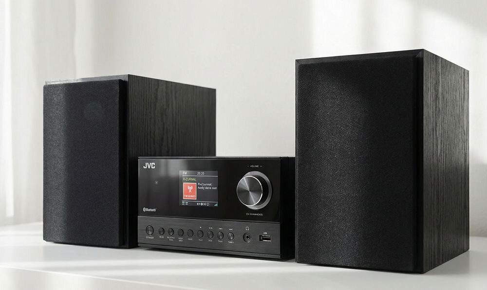 Czarna wieża audio z dwoma głośnikami po bokach. Na centralnym panelu widoczny jest kolorowy wyświetlacz LCD oraz przyciski sterujące.