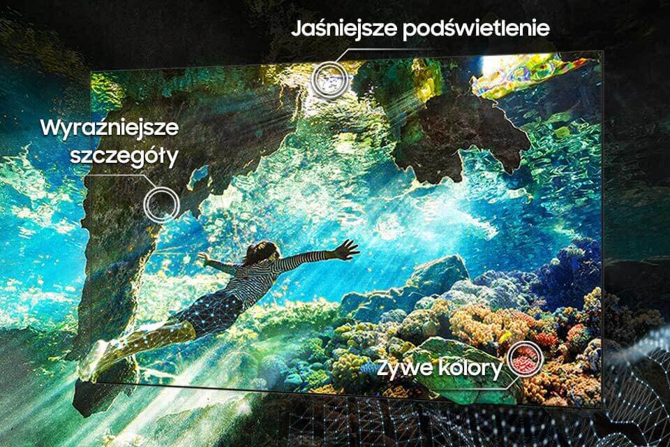 Obraz przedstawia osobę pływającą pod wodą wśród kolorowych raf koralowych. Na obrazie znajdują się napisy: \'Jaśniejsze podświetlenie\', \'Wyraźniejsze szczegóły\', \'Żywe kolory\'.