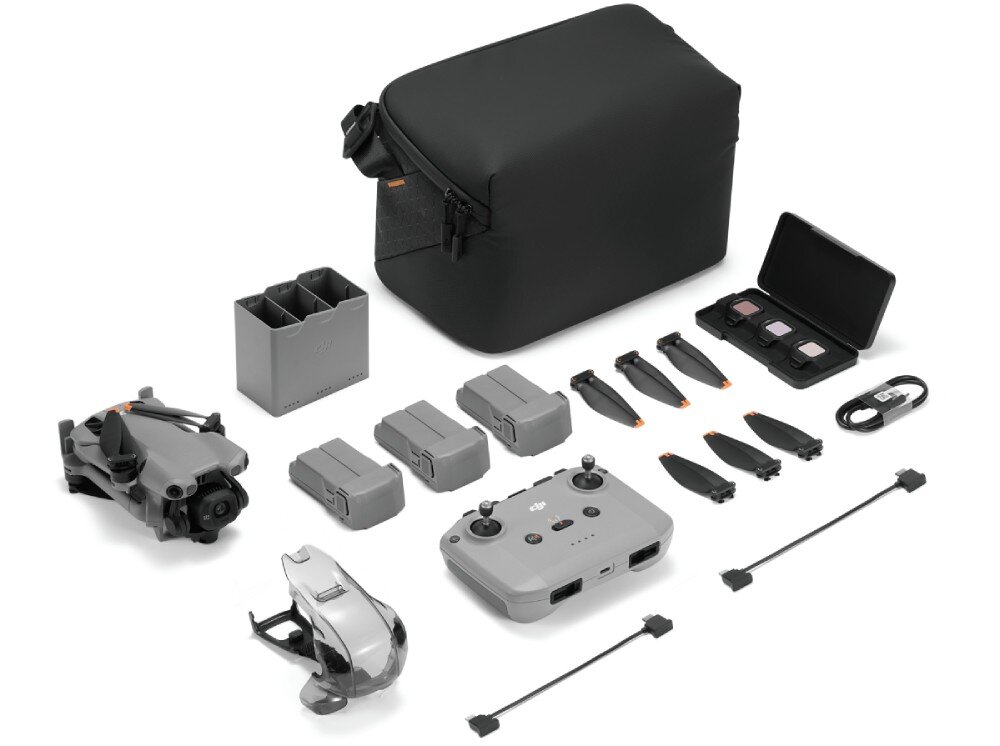 Na obrazie widoczny jest zestaw drona z akcesoriami, w tym torba, kontroler, baterie, śmigła, ładowarka i etui z filtrami. Wszystkie elementy są ułożone na białym tle.
