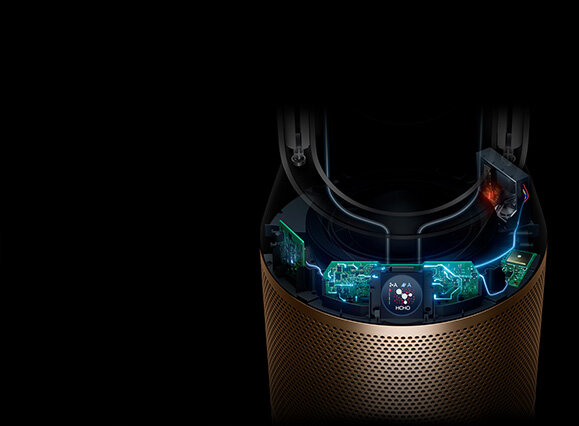 Obraz przedstawia fragment oczyszczacza powietrza z widocznymi elementami elektronicznymi i wyświetlaczem. Obudowa ma złoty kolor z perforacją, a na wyświetlaczu widoczny jest napis \'AUTO\'.