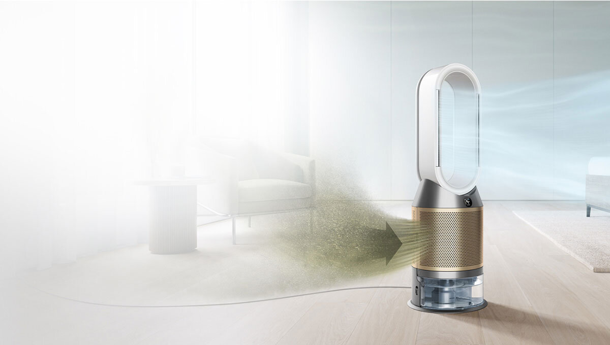Na obrazie znajduje się oczyszczacz powietrza z wentylatorem o nowoczesnym designie, umieszczony w jasnym pomieszczeniu. Widać strzałkę wskazującą przepływ powietrza przez urządzenie.