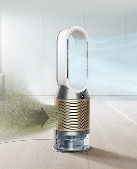 Na obrazie widoczny jest oczyszczacz powietrza z wentylatorem o nowoczesnym designie, z dużym owalnym otworem na górze i perforowaną obudową. Widać strumień powietrza wchodzący z jednej strony i wychodzący z drugiej, co sugeruje działanie urządzenia.