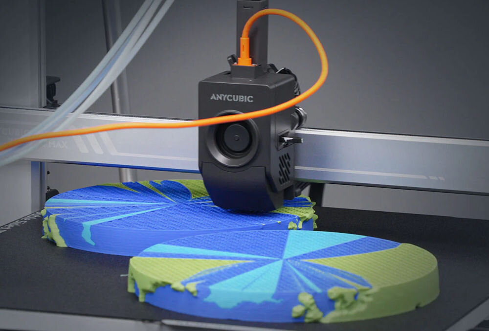 Drukarka 3D ANYCUBIC Kobra 3 Max Combo Wi-Fi, LAN + Dysza + Filament PLA Czarny Zbliżenie na głowicę drukarki 3D Anycubic Kobra 3 Max w trakcie aktywnego drukowania dużego, płaskiego, wielokolorowego obiektu (niebiesko-zielonego) z widoczną strukturą wypełnienia współpraca z filamentami PLA TPU PETG szeroka kompatybilność i możliwości zastosowania