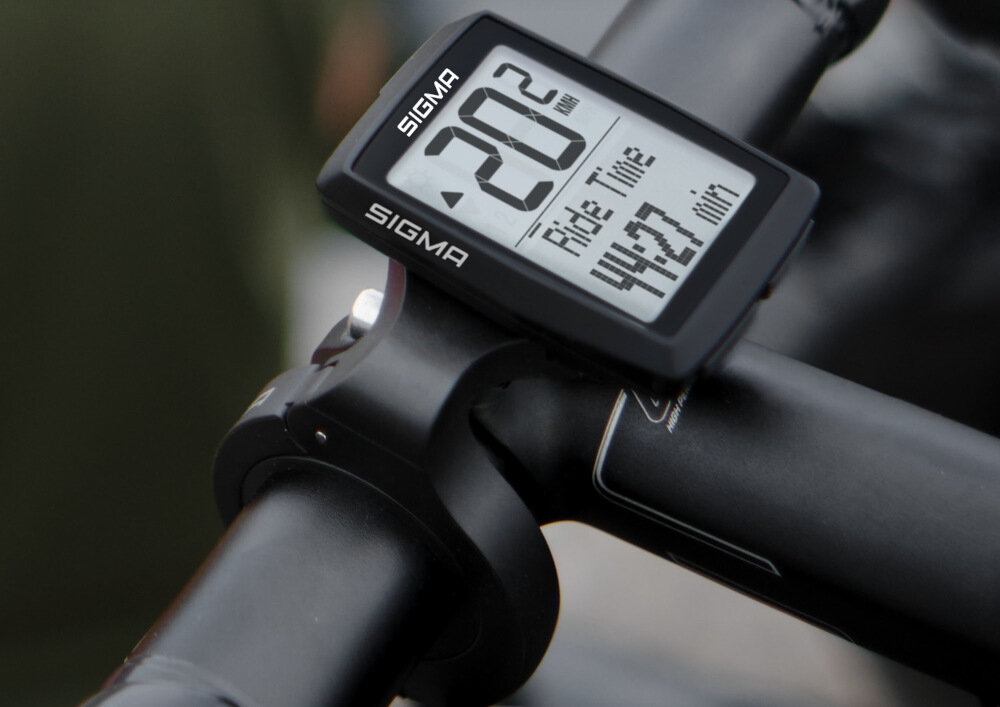 Licznik rowerowy z logo SIGMA zamontowany na kierownicy, wyświetlający prędkość 20.2 km/h i czas jazdy 44:27 min.