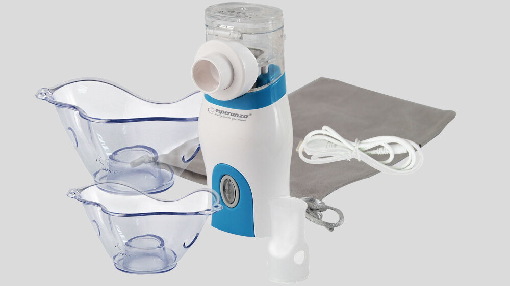 Na obrazie znajduje się biało-niebieski inhalator nebulizator z logo \'Esperanza\', dwa przezroczyste pojemniki, kabel zasilający oraz szara torba. Wszystkie elementy są ułożone na szarym tle.