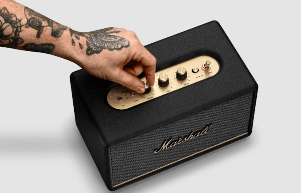 MARSHALL Acton III głośnik mobilny ikoniczny design mosiężne pokrętła, głośnik od góry na jasnym tle, ręka trzymająca pokrętło