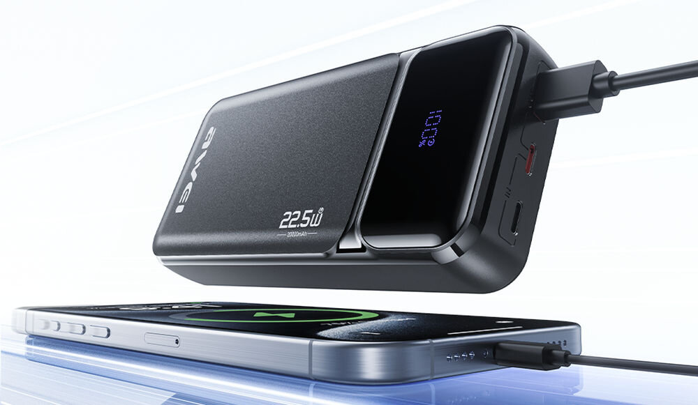 Na obrazie widać czarny powerbank z wyświetlaczem pokazującym \'100%\' oraz telefon podłączony do niego kablem. Na powerbanku widoczne są napisy \'AWEI\' i \'22.5W\'.
