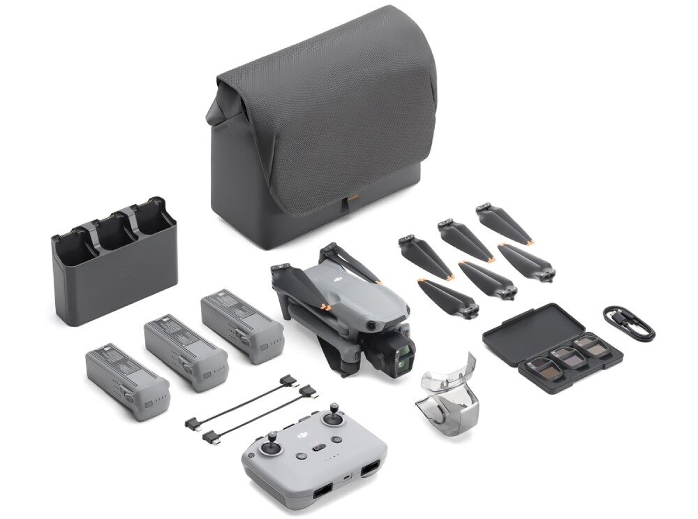 Na obrazie widoczny jest zestaw drona z akcesoriami, w tym torba, kontroler, trzy baterie, ładowarka, śmigła i filtry. Wszystkie elementy są w odcieniach szarości i czerni.