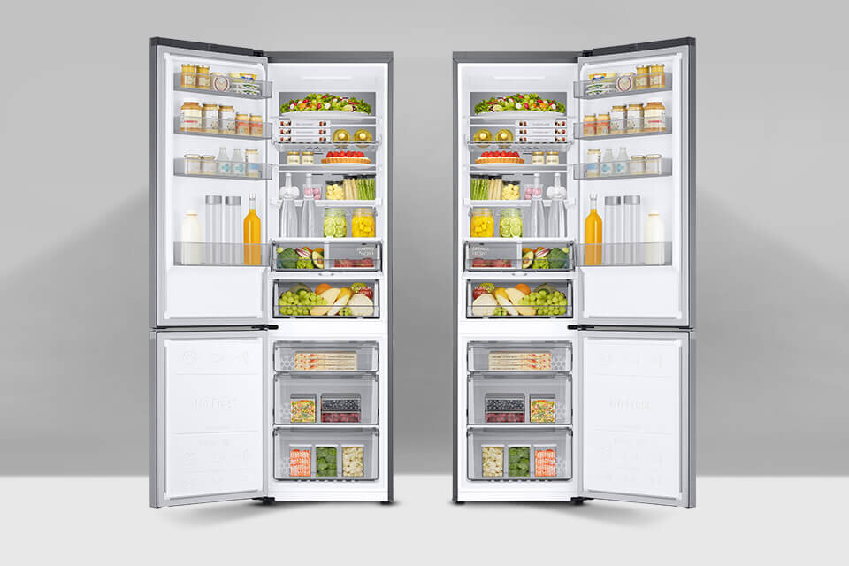 Dwie otwarte lodówki w kolorze szczotkowanej stali nierdzewnej, wypełnione różnorodnymi produktami spożywczymi, takimi jak owoce, warzywa, napoje i słoiki. Wnętrze lodówek jest jasno oświetlone, a produkty są uporządkowane na półkach i w szufladach.