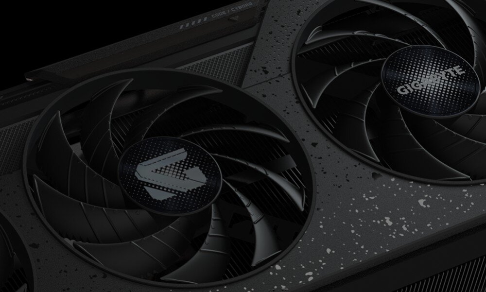 Karta graficzna GIGABYTE Radeon RX 9060XT GAMING OC 16G Dwa wentylatory karty graficznej w zbliżeniu, z widoczną teksturą przypominającą ciemny metal z jasnymi kropkami, wygląd, obudowa