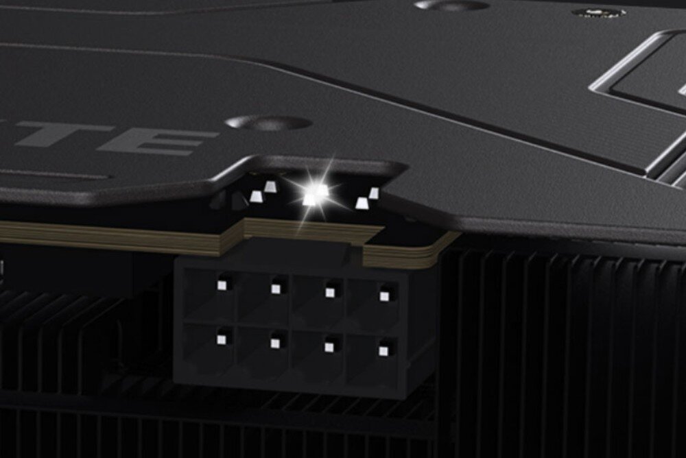 Karta graficzna GIGABYTE Radeon RX 9060XT GAMING OC 16G Zbliżenie na złącze zasilania z błyszczącym wskaźnikiem świetlnym umieszczonym nad metalowym backplate'em, backplate, ochrona, wskaźnik zasilania