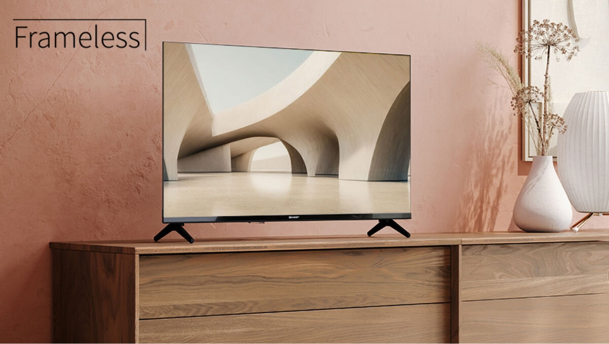 Telewizor SHARP 40HA1705E - Elegancki, bezramkowy wygląd, telewizor stojący na komodzie, obok wazonu z kwiatem