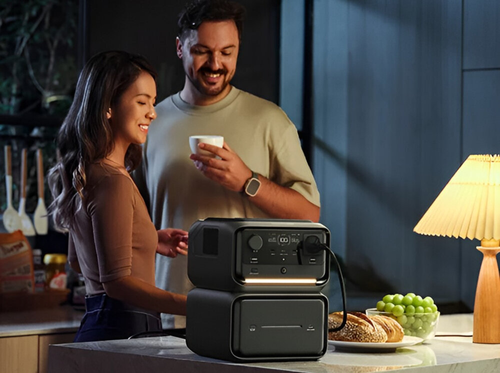 Stacja zasilania ECOFLOW River 3 Max Plus 858Wh Wireless kuchnia stacja stoi na blacie kuchennym w tle dwie osoby rozmawiają pojemność 858 Wh pobierający 10 W może działać nawet około 61,1 godziny urządzenie o poborze 600 W przez około godzinę