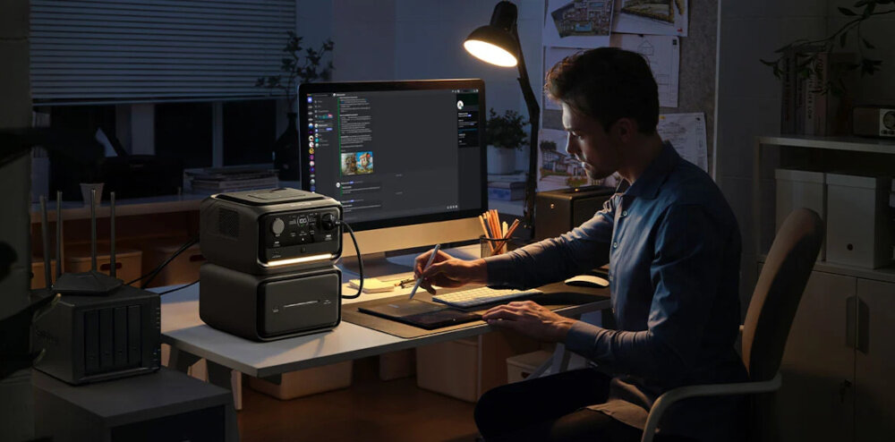 Stacja zasilania ECOFLOW River 3 Max Plus 858Wh Wireless pokój biuro osoba pracuje przy komputerze komputer podłączony do stacji funkcja UPS z czasem przełączania poniżej 10 ms może również przekazać do komputera lub serwera NAS informację o niskim poziomie energii ograniczasz ryzyko utraty niezapisanych plików