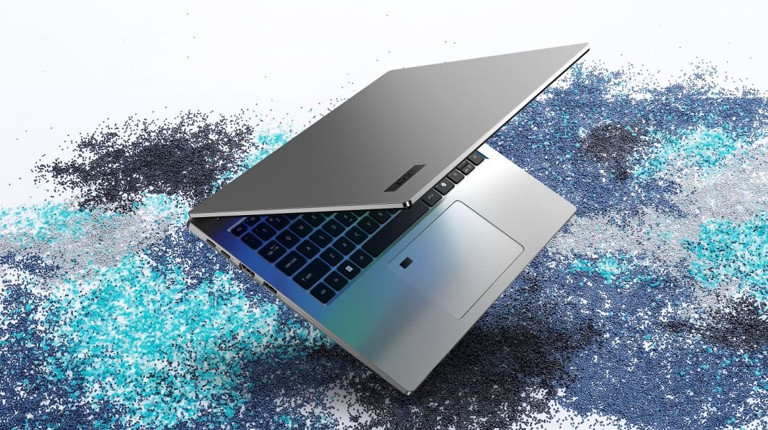 Laptop ACER TravelMate TMP214-56-TCO NX.BD3EP.002 z certyfikatem MIL-810H - srebrna obudowa z klawiaturą i touchpadem na tle kolorowych drobinek