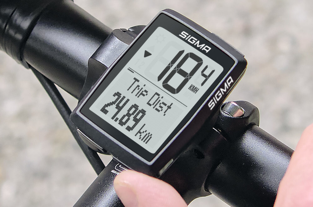 Licznik rowerowy z wyświetlaczem pokazującym prędkość 18.4 km/h oraz dystans 24.89 km. Na obudowie widoczne jest logo SIGMA.