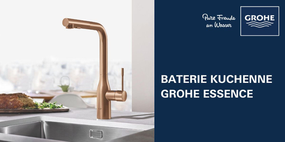 Na obrazie widoczna jest bateria kuchenna w kolorze miedzianego złota zamontowana przy zlewie. Obok znajduje się napis \'BATERIE KUCHENNE GROHE ESSENCE\' oraz logo GROHE.