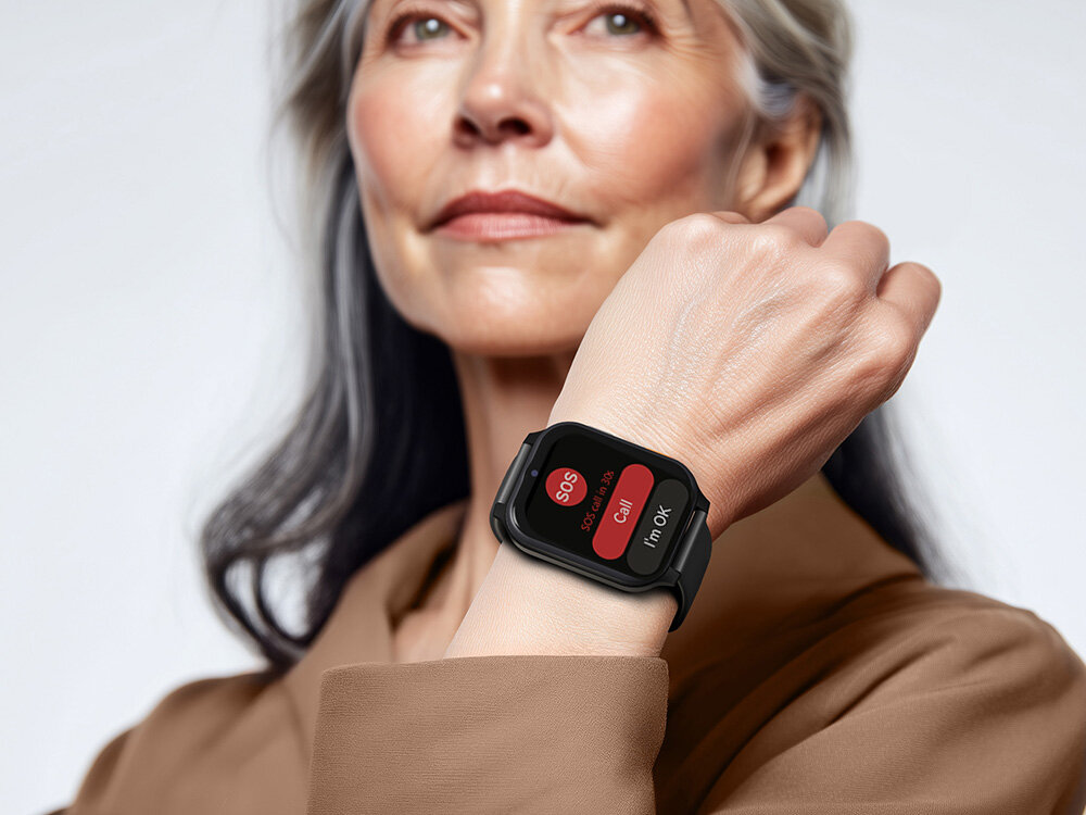 Osoba nosi czarny smartwatch z widocznym ekranem, na którym znajdują się przyciski z napisami: \'SOS\', \'Call\', \'i\'m OK\'.